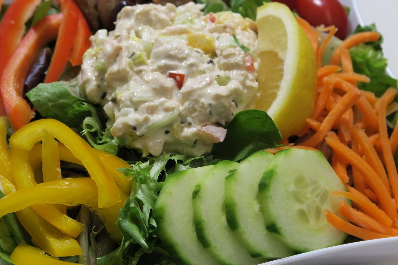 Fresh Salads A colorful salad with mixed greens, vegetables, and a creamy dressing on top.